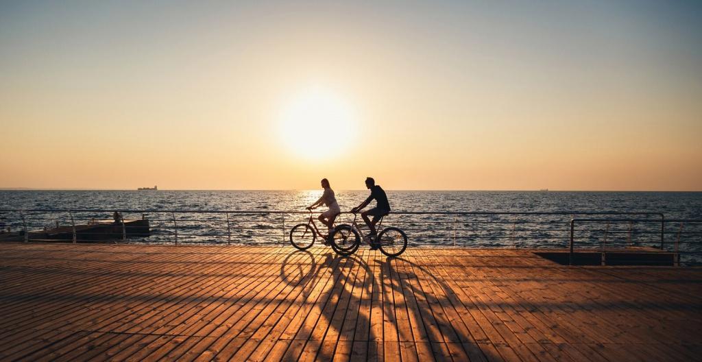 lifestyle design - perfil de duas pessoas andando de bicicleta, em frente ao mar, com um por do sol